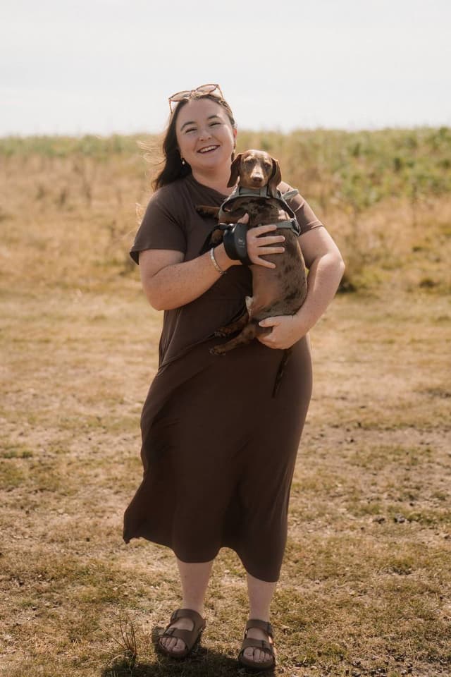 Beth, the founder of Graceful Studio, holding her dachshund outdoors