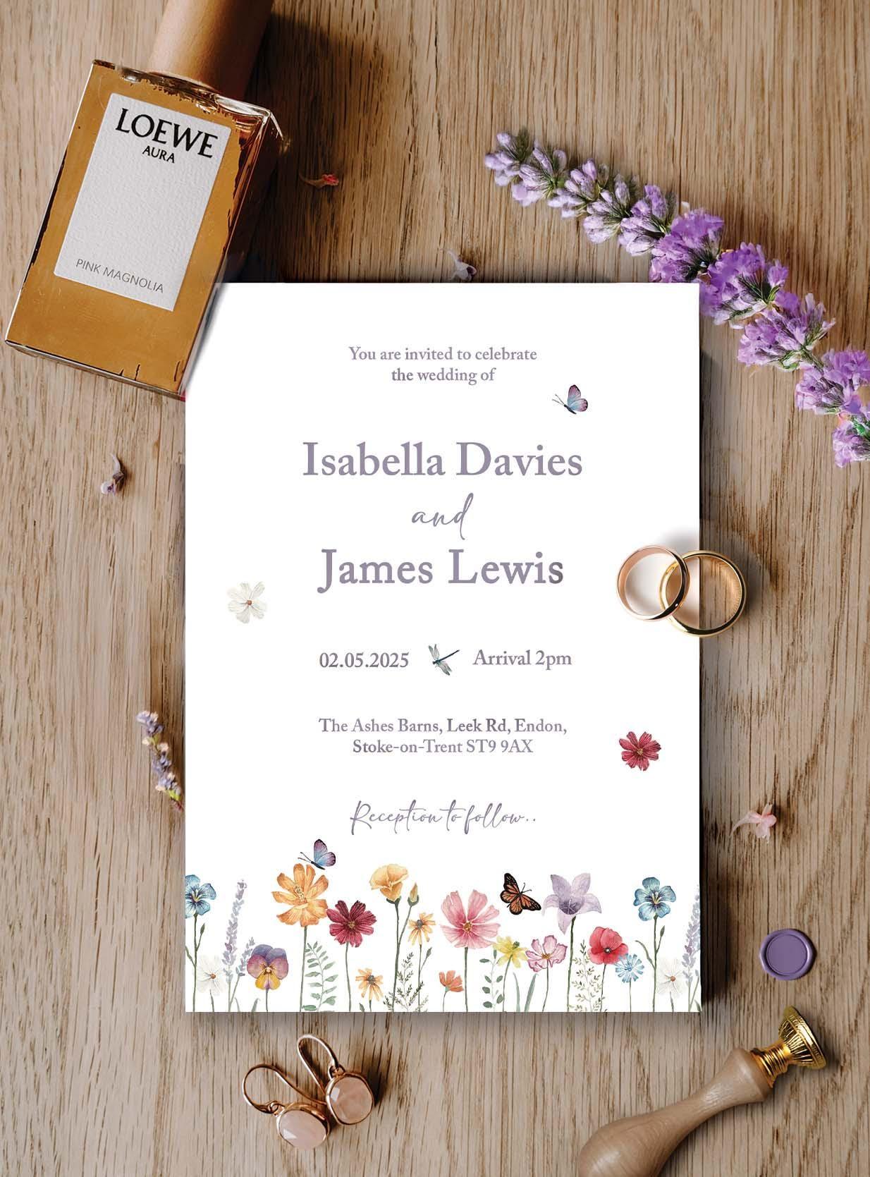 Watercolour wildflower wedding invitation for Isabella Davies and James Lewis on a wooden table, with gold wedding rings, a lilac wax seal, a wooden wax seal stamp and sprigs of lavender