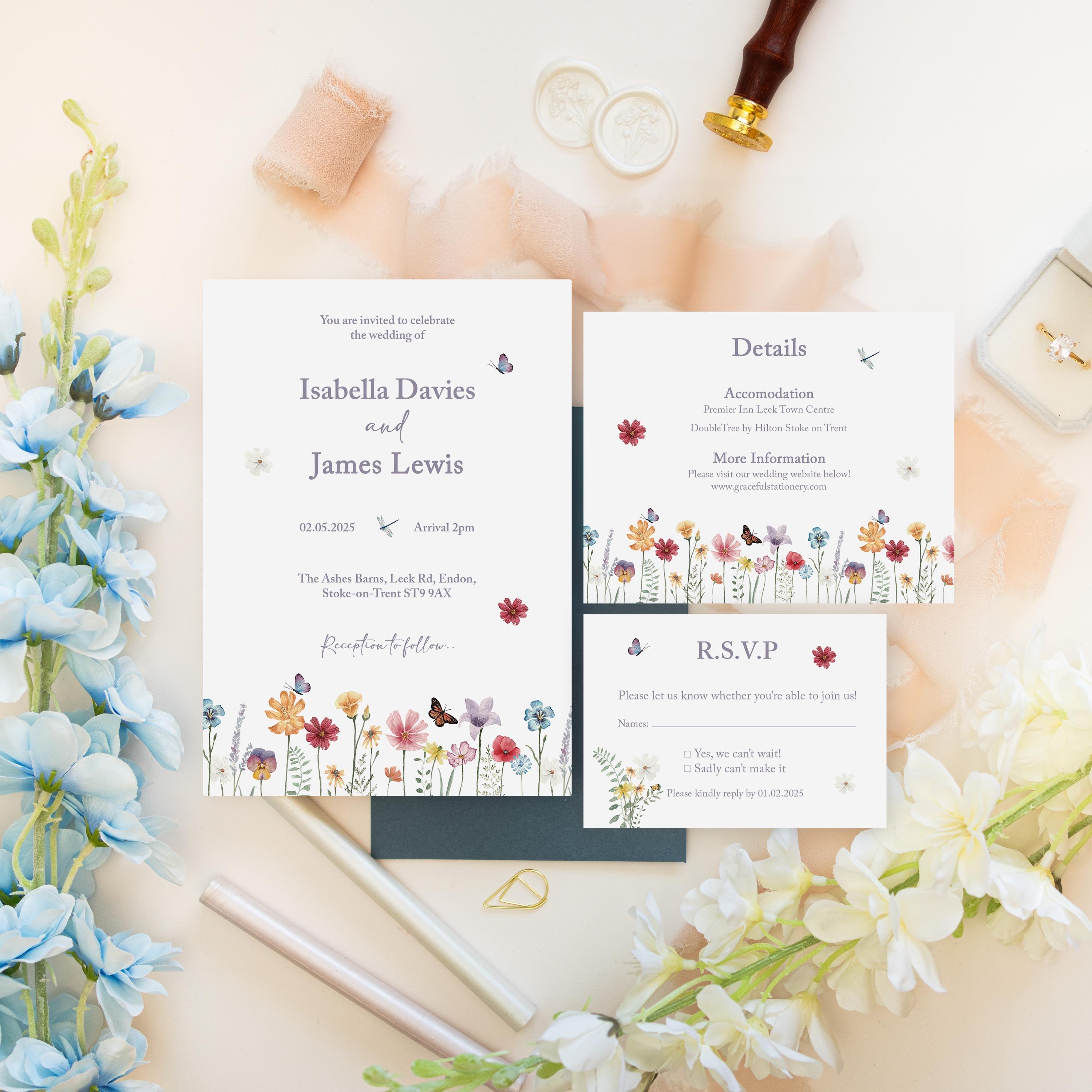 Watercolour wildflower wedding invitation for Isabella Davies and James Lewis with a matching details card and RSVP card on a dark blue envelope, with ivory wax seals, a wax seal stamp, peach silk ribbon and a gold clip